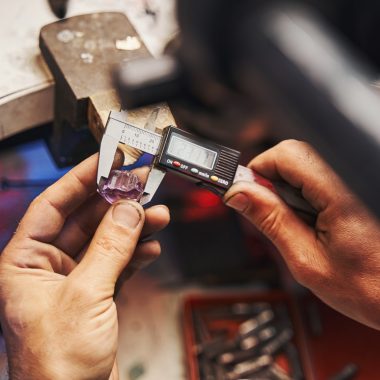 Jewelry store worker working with digital caliper while checking the size of gemstone and looking at readings on display